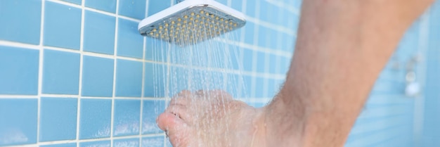 Foto mann wäscht seine füße aus sand unter der dusche am strand in der nähe