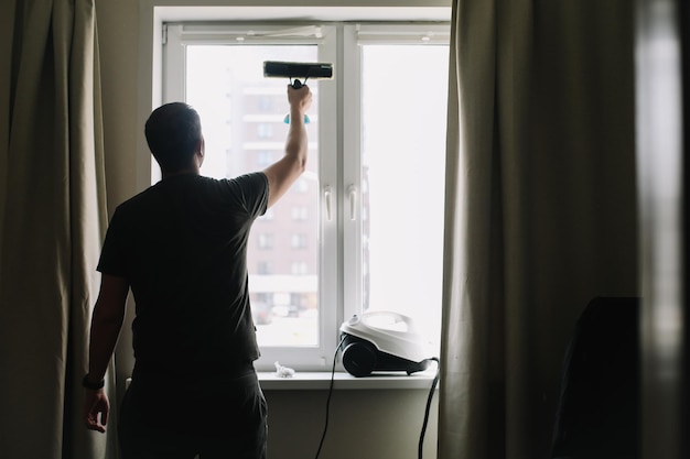 Mann wäscht und putzt Fenster zu Hause Hausarbeit und Haushaltshygiene