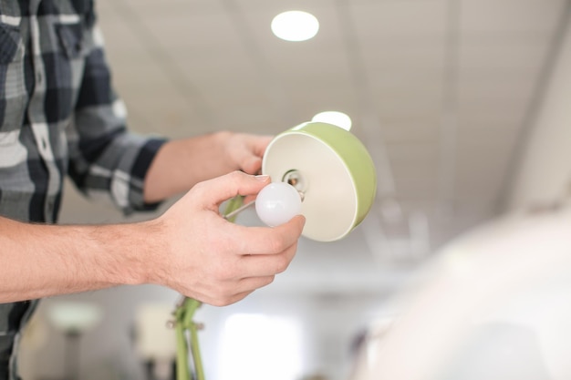 Mann wechselt zu Hause Glühbirne in Lampe