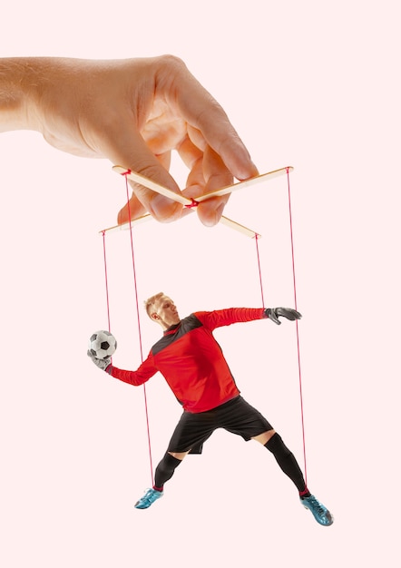 Foto mann wie eine marionette in den händen von jemandem auf rosa hintergrund. konzept der unfairen manipulation, ausbeutungsphysik, mentale technik, motivation. puppen und ihre meister. besessene beziehung.