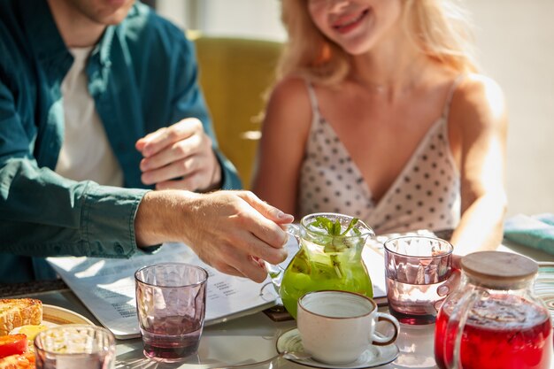 Mann wird süßes Getränk in Gläser für Frau in leichtem Café gießen