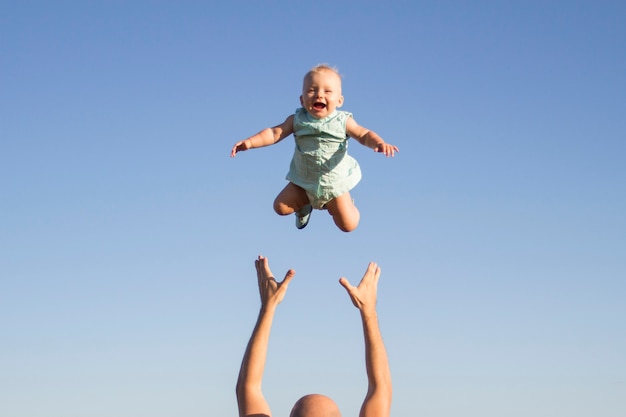Mann wirft Baby gegen den blauen Himmel