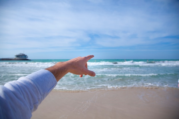 Mann zeigt auf das Meer