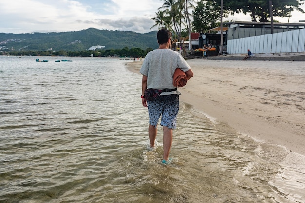 Mann zu Fuß entlang der Küste an einem Strand auf der Insel Koh Samui Thailand