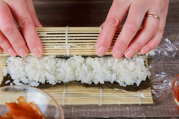 Mannes hände halten bambusmatte. bambusmatte und kochbrett. küchenchef macht leckeres sushi.