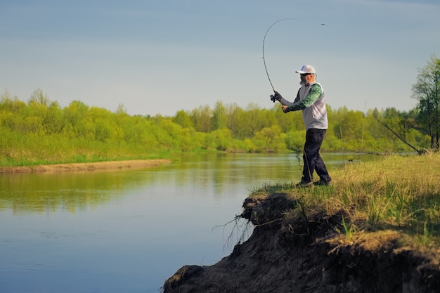 Mannfische mit dem Spinnen auf Flussufer