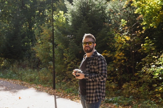 Mannfotograf, der ein Foto mit einer Vintage-Kamera auf dem grünen Park der Stadt macht, kopiert Platz und Platz für Text-Freizeitaktivitäten und Hobby-Konzept