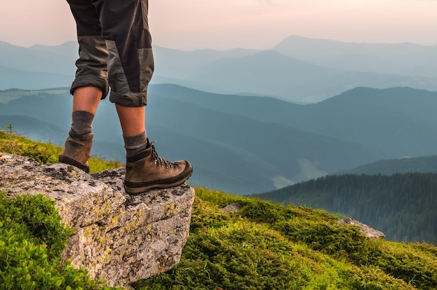 Mannfüße in Wanderschuhen auf dem Felsen in den Abendbergen