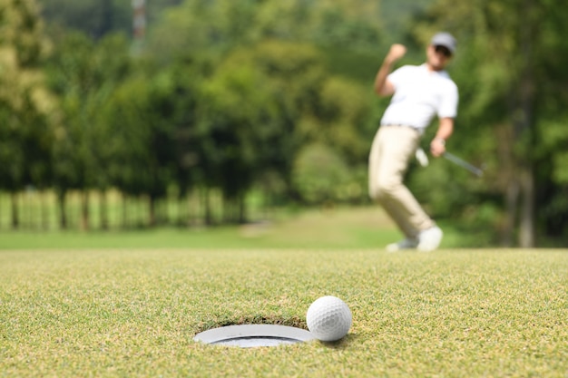 Manngolfer, der nach einem Golfball auf einem Golfgrün jubelt