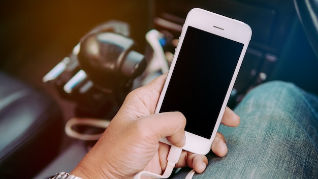 Mannhände, die intelligentes Telefon innerhalb eines Autos halten