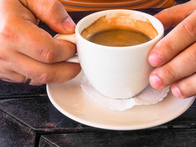 Mannhände, die Tassen Kaffee auf Holztischhintergrund halten