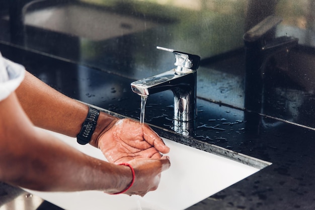 Mannhände reiben mit Seife und Wasser in Waschbecken