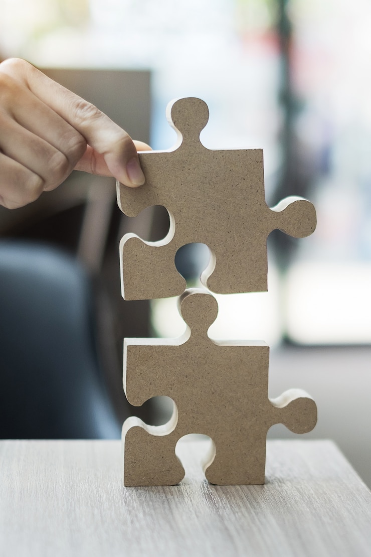 Foto mannhände verbinden paar puzzle über tisch, geschäftsmann hält holzpuzzle im büro.