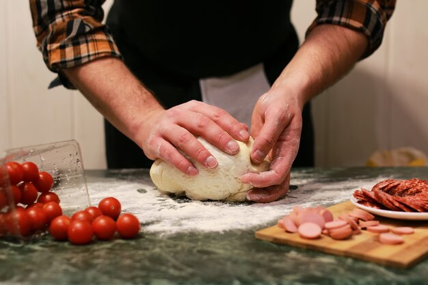 Mannhand bereitet Pizzateigbelag vor