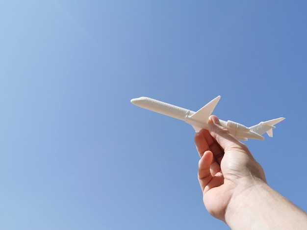 Mannhand, die Flugzeug mit Hintergrund des blauen Himmels hält