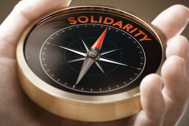 Mannhand, die Kompass mit Nadel hält, die das Wort Solidarität zeigt. Konzept der Soziologie. Zusammengesetztes Bild zwischen einer Handphotographie und einem Hintergrund 3D.