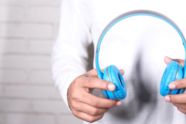 Mannhand, die Kopfhörer auf blauem Hintergrund hält