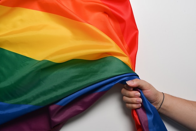 Mannhand, die LGBT-Stolzflagge auf weißem Hintergrund hält. LGBT-Konzept.