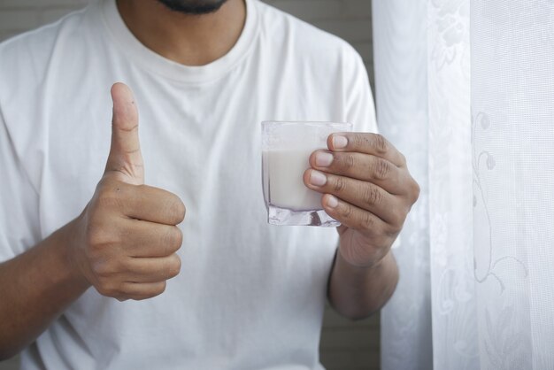 Mannhand hält Glas Milch am frühen Morgen