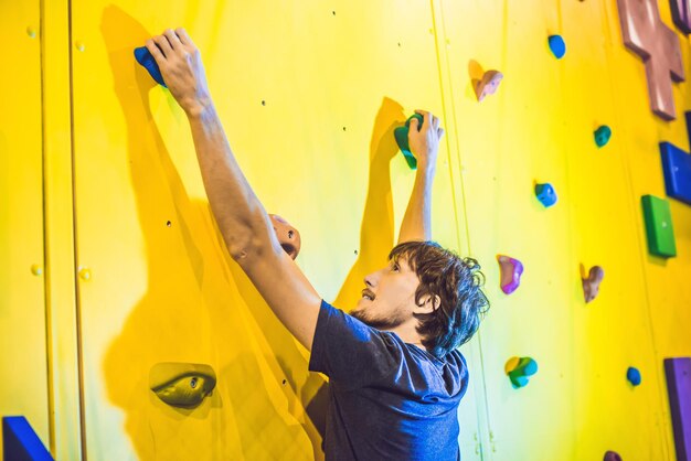 Mannkletterer auf künstlicher Kletterwand in Boulderhalle