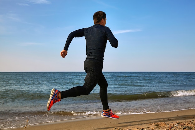 Mannläufer an der Küste im Sportoutfit. Cardio-Joggen