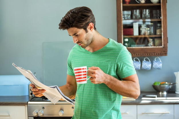 Mannlesezeitung beim Trinken des Kaffees in der Küche