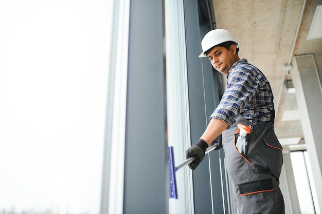 Mannlicher Hausmeister reinigt Fenster im Büro