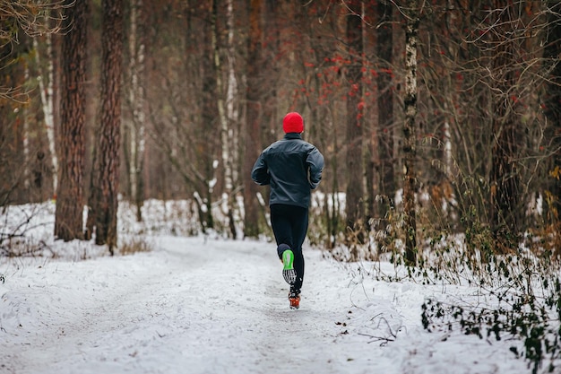 Mannlicher Läufer läuft auf einem Weg im schneebedeckten Winterwald