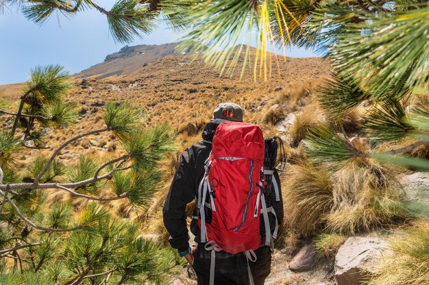 Mannlicher Wanderer mit Rucksack beobachtet den Gipfel des Berges Konzept Motivation und Zielerreichung