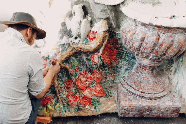 Mannmosaikmeister in der Hutherstellung Smalt-Glasmosaikplatte Männlicher Mosaikkünstler bei der Arbeit