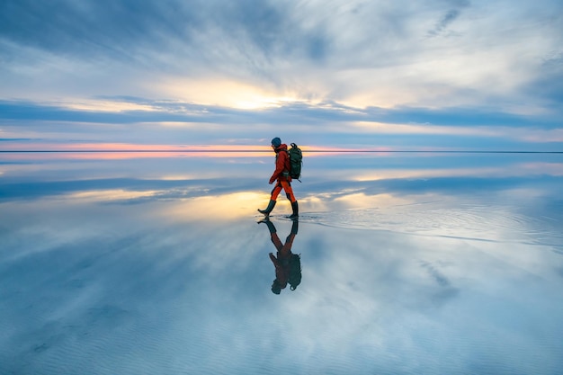 Mannreisender, der bei Sonnenuntergang auf dem See spazieren geht