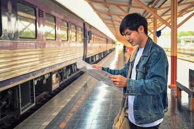 Mannreisender, der eine Karte auf Bahnhof liest