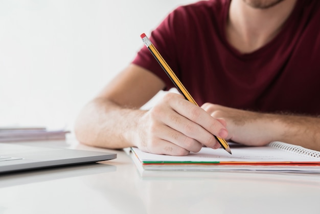 Mannschreiben auf seinem Notizblock mit Bleistift