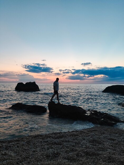 Mannsilhouette, die den Blick auf den Sonnenuntergang über dem Meer genießt