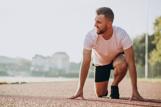 Mannsportler, der morgens im Stadion joggt