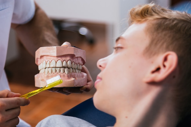 Foto mannzahnarzt zeigt seinem patienten in der klinik zahnersatzzähne bei zahnarztpraxen