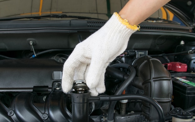 mano abra la cubierta metálica de la válvula en un radiador para la refrigeración del motor