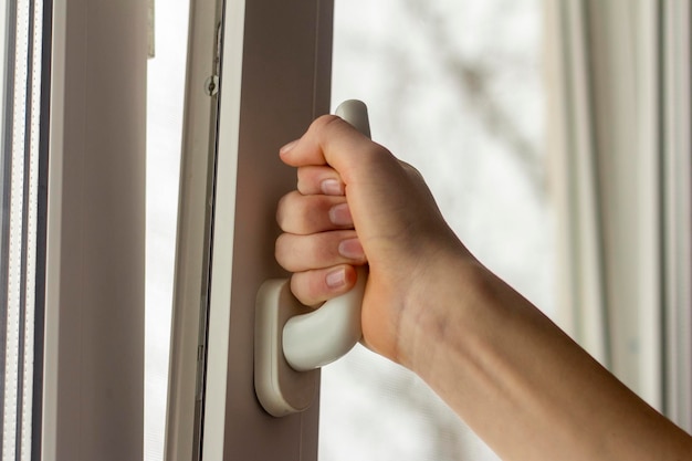 Foto la mano del adolescente abre la ventana para ventilar la habitación.