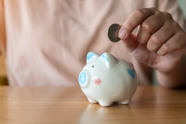 Mano adulta ahorrando poner monedas en una alcancía Ahorrar dinero para el futuro concepto de jubilación