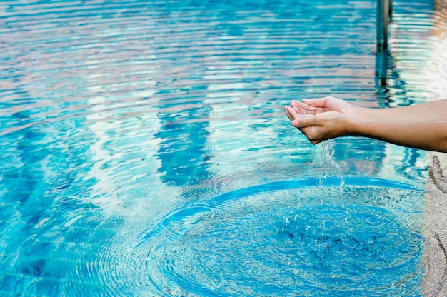 Mano y agua tocan el agua azul. Para refrescar el concepto de jugar agua limpia con espacio de copia.