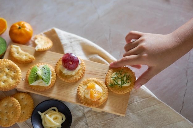 Una mano alcanza una galleta de queso con fruta.