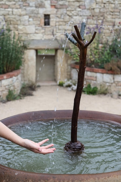 una mano alcanzando bajo el agua que brota de una fuente