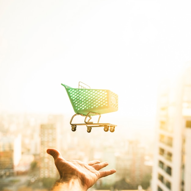 Foto mano alcanzando para carrito de supermercado en el fondo borroso