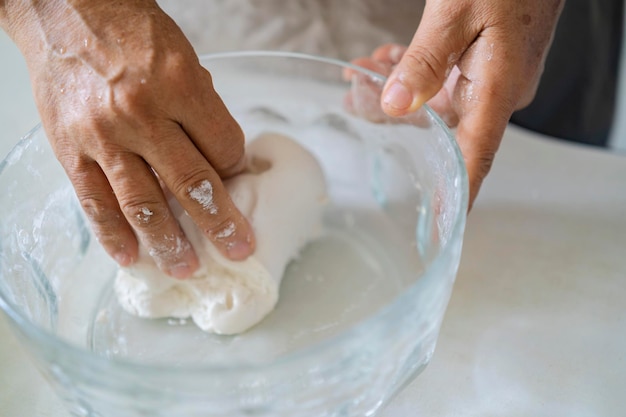 La mano de un anciano una mujer asiática amasando los ingredientes para hacer masa de pan