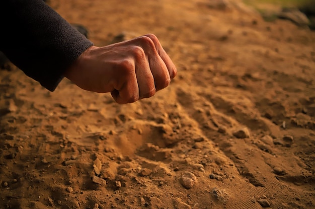 Foto una mano apunta a una bola de arena en la arena.