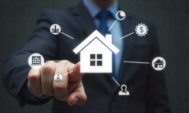 Una mano apuntando a un icono de casa en una pantalla digital rodeada de varios bienes raíces y finanzas