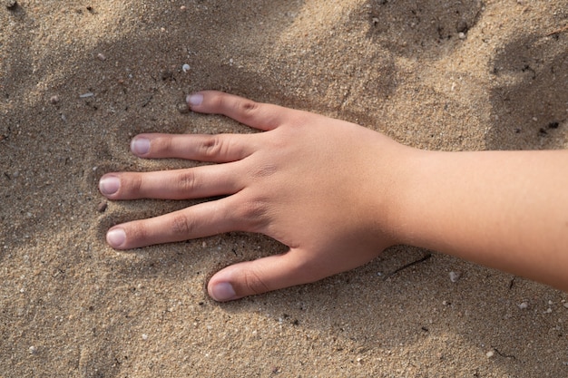 Mano en la arena de la playa