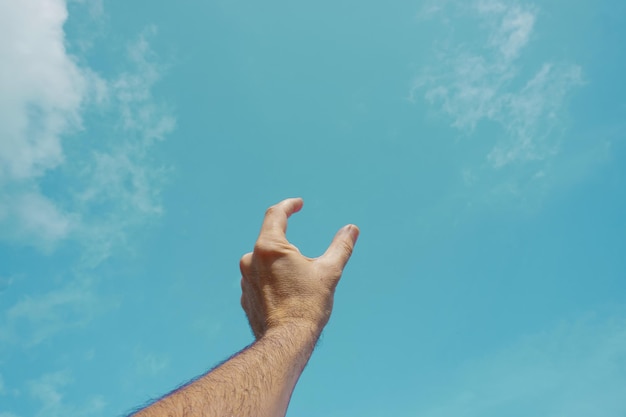 Foto mano arriba gesticulando en el cielo azul, sentimientos y emociones