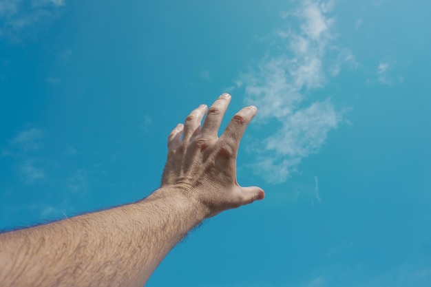 Foto mano arriba gesticulando en el cielo azul, sentimientos y emociones