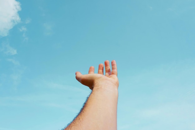 mano arriba gesticulando en el cielo azul, sentimientos y emociones